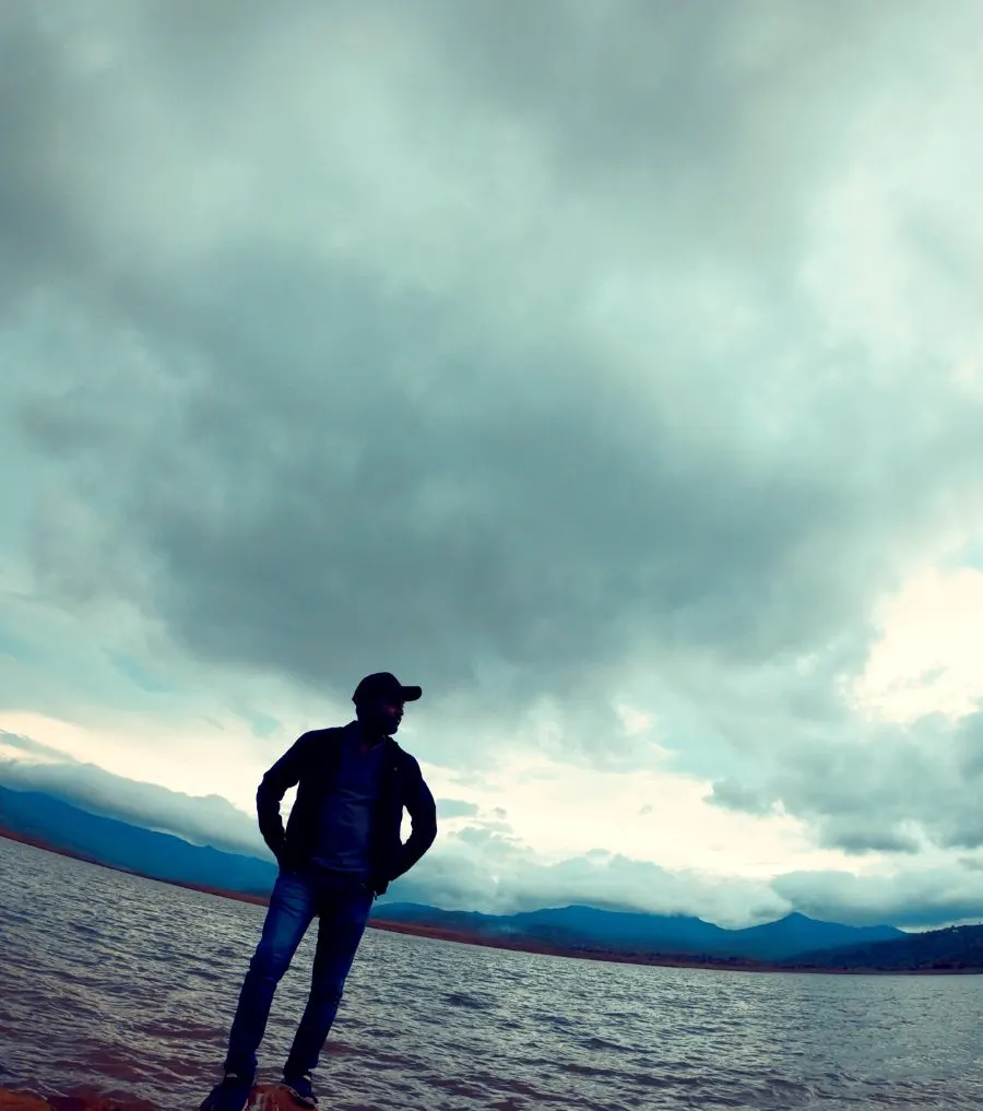 Tushar standing on a rock under a wide cloudy sky